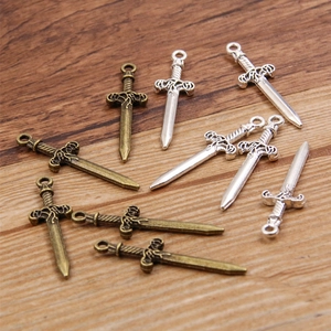 Silver and bronze alloy sword charms for DIY jewelry making on a wooden background