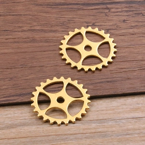 Macro shot of gold steampunk hollow gear charms for DIY jewelry on wooden surface