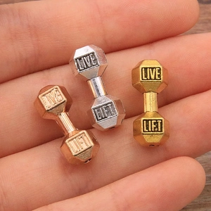 Macro shot of dumbbell-shaped gym beads with Live Lift engraving in gold, silver and rose gold