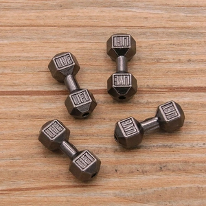 Macro shot of gunblack dumbbell beads with 'LIVE' and 'LIFT' engraving for DIY jewelry