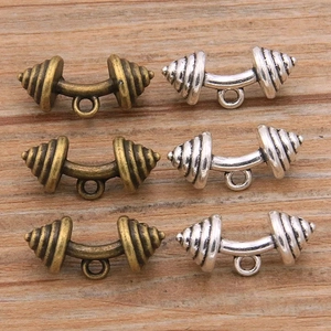 Pendentifs haltères vintage en bronze et argent pour bijoux DIY sur fond de bois naturel
