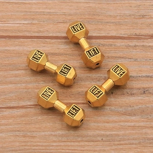 Macro shot of gold dumbbell beads with Live and Lift engraving for DIY jewelry making
