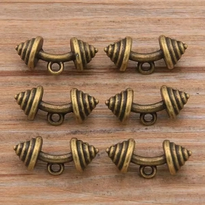 Détail de pendentifs haltères en bronze vintage sur bois pour la création de bijoux DIY