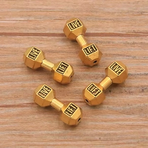 Golden dumbbell-shaped DIY jewelry beads engraved with LIVE and LIFT on wooden surface