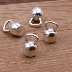Détail de quatre breloques de kettlebell argentées sur un fond en bois texturé