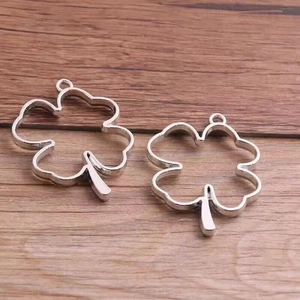 Silver hollow clover flower frame charms for DIY necklace making on wooden background