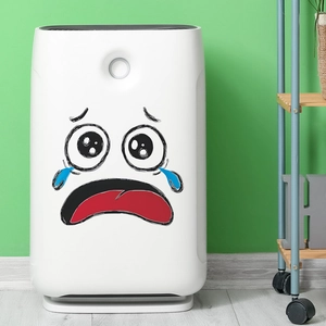 White air purifier featuring a crying cartoon face sticker on a green wall background