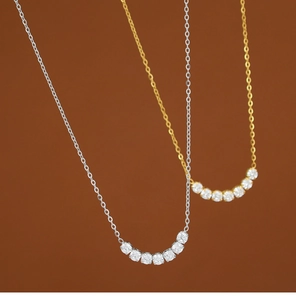 Detalle macro de collares de sonrisa en plata y oro con siete piedras de circonita