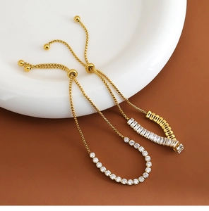 Detalle de pulsera tenis ajustable dorada con circonitas cúbicas redondas y tipo baguette