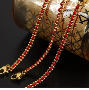 Vista detallada de la pulsera de cordón rojo trenzado con cuentas doradas y cierre de langosta