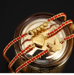 Vista detallada de pulseras de cuerda roja trenzada con dijes de oro corazón y mariposa