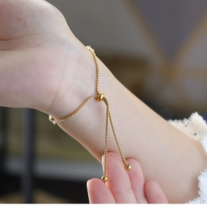 Primer plano de pulsera ajustable de cadena de caja dorada con cuenta deslizante y circonita