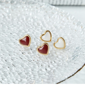 Primer plano de pendientes con forma de corazón rojos y blancos con borde dorado