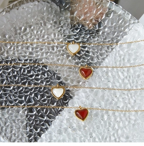 Primer plano de collares de corazón en ágata roja y nácar blanco con cadenas doradas