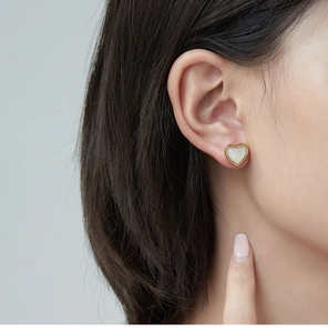 Primer plano de pendientes de corazón minimalistas con borde dorado e incrustación de nácar