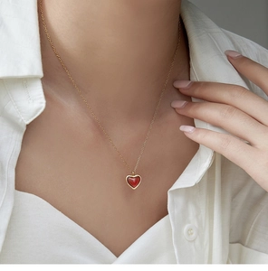 Detalle de colgante de corazón de ágata roja en cadena dorada sobre lino blanco