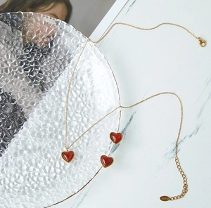 Detalle de collar con colgante de corazón dorado y sello K18 en la cadena de extensión