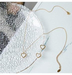 Vista detallada del conjunto de joyas de corazón en oro K18 sobre mármol y vidrio