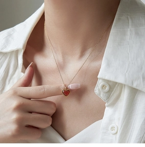 Primer plano de collar con corazón de ágata roja y cadena dorada usado por una modelo