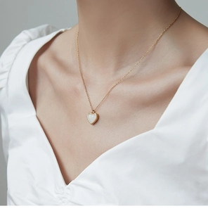 Primer plano de una modelo luciendo un collar con colgante de corazón dorado y piedra