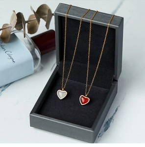 Primer plano de collares de ágata roja en forma de corazón en caja de regalo gris