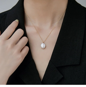 Detail van een barokke parelketting met 18K gouden afwerking gedragen door een model