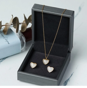 Detalle de conjunto de collar y pendientes de corazón con nácar blanco en caja de regalo negra