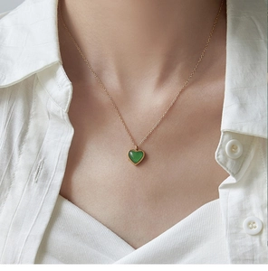 Primer plano de un collar con colgante de corazón en ágata verde y cadena dorada en una modelo