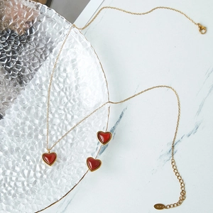 Elegante conjunto de collar y pendientes de oro K18 con corazón de ágata roja sobre mármol