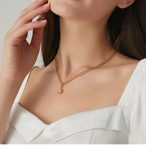Detail of double-layer gold necklace featuring a round pink agate stone pendant on a model