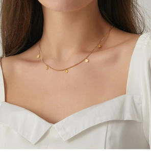 Primer plano de collar dorado con colgantes de picas en modelo con top blanco