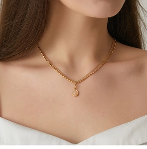 Detail of layered gold titanium necklace with double chains and a round gemstone pendant