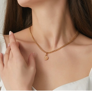 Close-up of double-layered gold necklace with pink stone pendant on a female model
