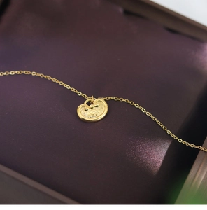 Detail shot of golden Ruyi long-life lock necklace pendant on dark velvet box