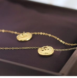 Macro shot of gold Ruyi lock pendant with intricate relief carvings and fine chain