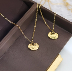 Detailed macro view of matte gold Longevity Lock pendants with traditional cloud relief pattern