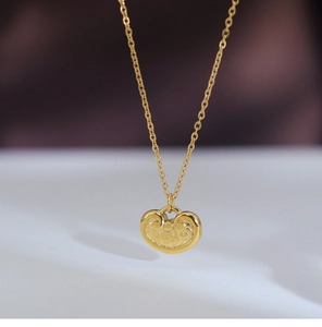 Macro shot of gold-plated ruyi lock pendant with intricate cloud pattern reliefs