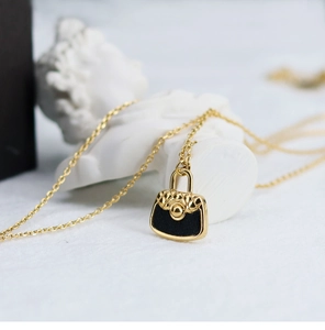 Detailed macro view of quilted black mini bag pendant necklace in 18K gold-plated steel
