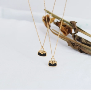 Detailed close-up of a mini black quilted bag pendant on a gold chain necklace