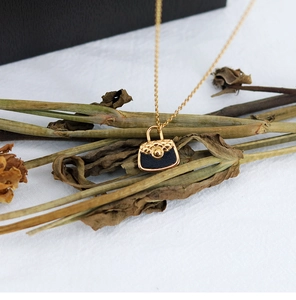 Detail of miniature quilted handbag pendant in gold and black on 18K gold-plated chain