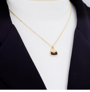Close-up of gold plated necklace with black quilted purse pendant on a professional model