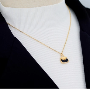 Detail of 18K gold plated necklace featuring a black quilted bag pendant with gold accents