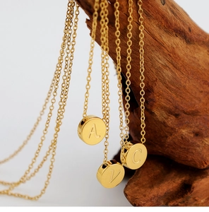 Detalle de collares con colgante de disco A V C en acero inoxidable chapado en oro 18K