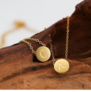 Primer plano de collares con iniciales de acero inoxidable chapado en oro de 18K