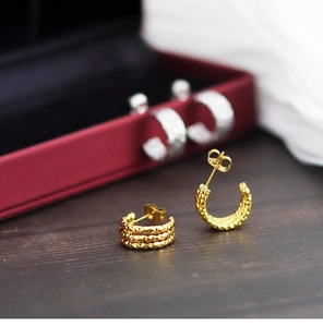 Makroaufnahme der 18k vergoldeten C-Ohrringe mit Diamant-Struktur und Herz-Details