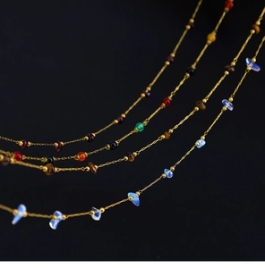 Macro detail of 18K gold plated necklaces with irregular natural gemstones on black background