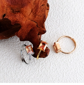 Detail of three adjustable four-prong geometric rings with champagne zircon on wood surface