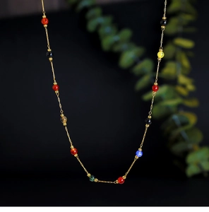Close-up of 18K gold chain necklace with colorful amethyst and tiger eye gemstone beads