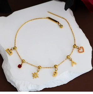 Detailed view of gold stainless steel bracelet with red ruby and star pendants