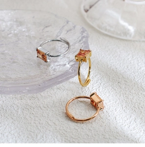 Close-up of three geometric square champagne zircon rings in silver, gold, and rose gold